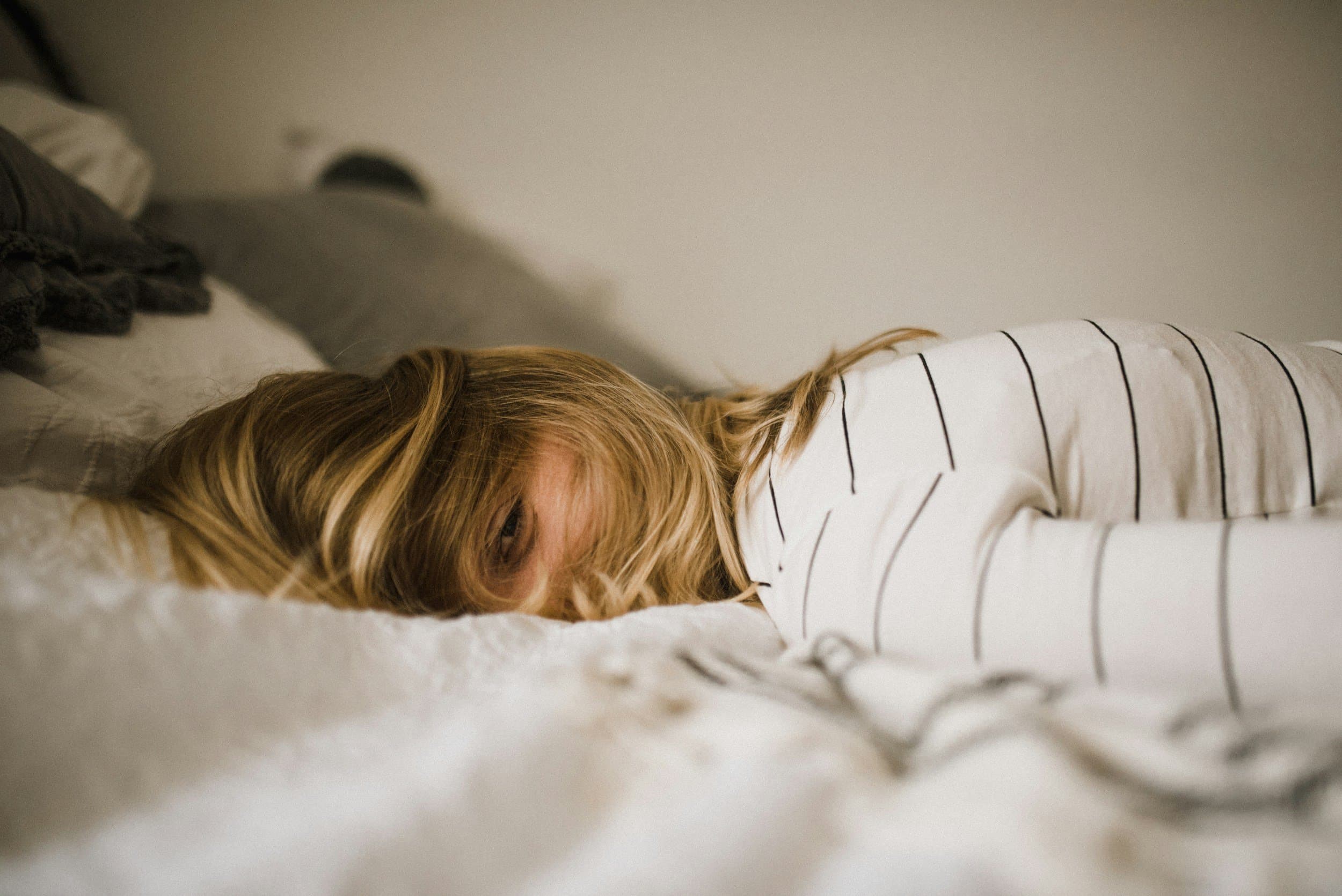 A woman lying face down on a bed looking tired and restless, reflecting the poor sleep quality linked to mouth breathing, at Align Dental Surgery