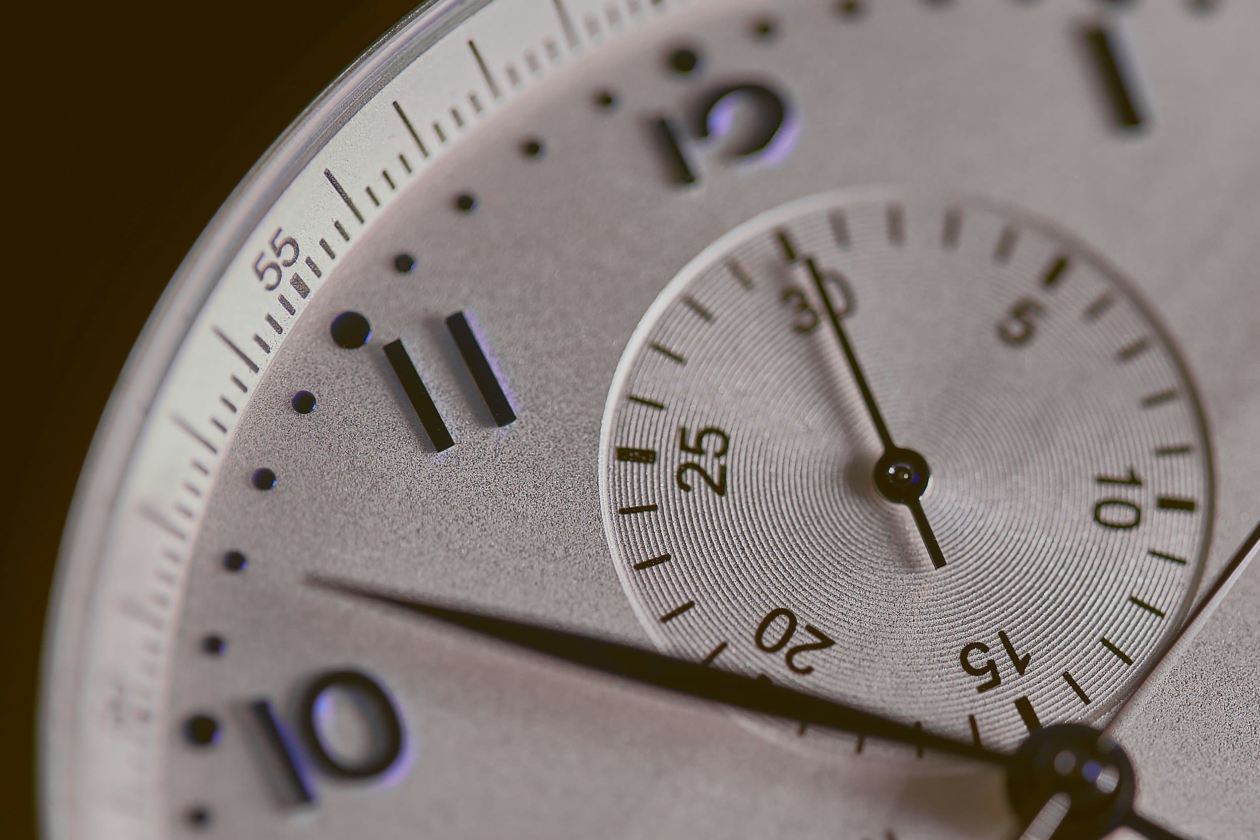 A macro close-up of a chronograph watch dial with a seconds subdial, reflecting the daily hours of retainer wear, at Align Dental Surgery