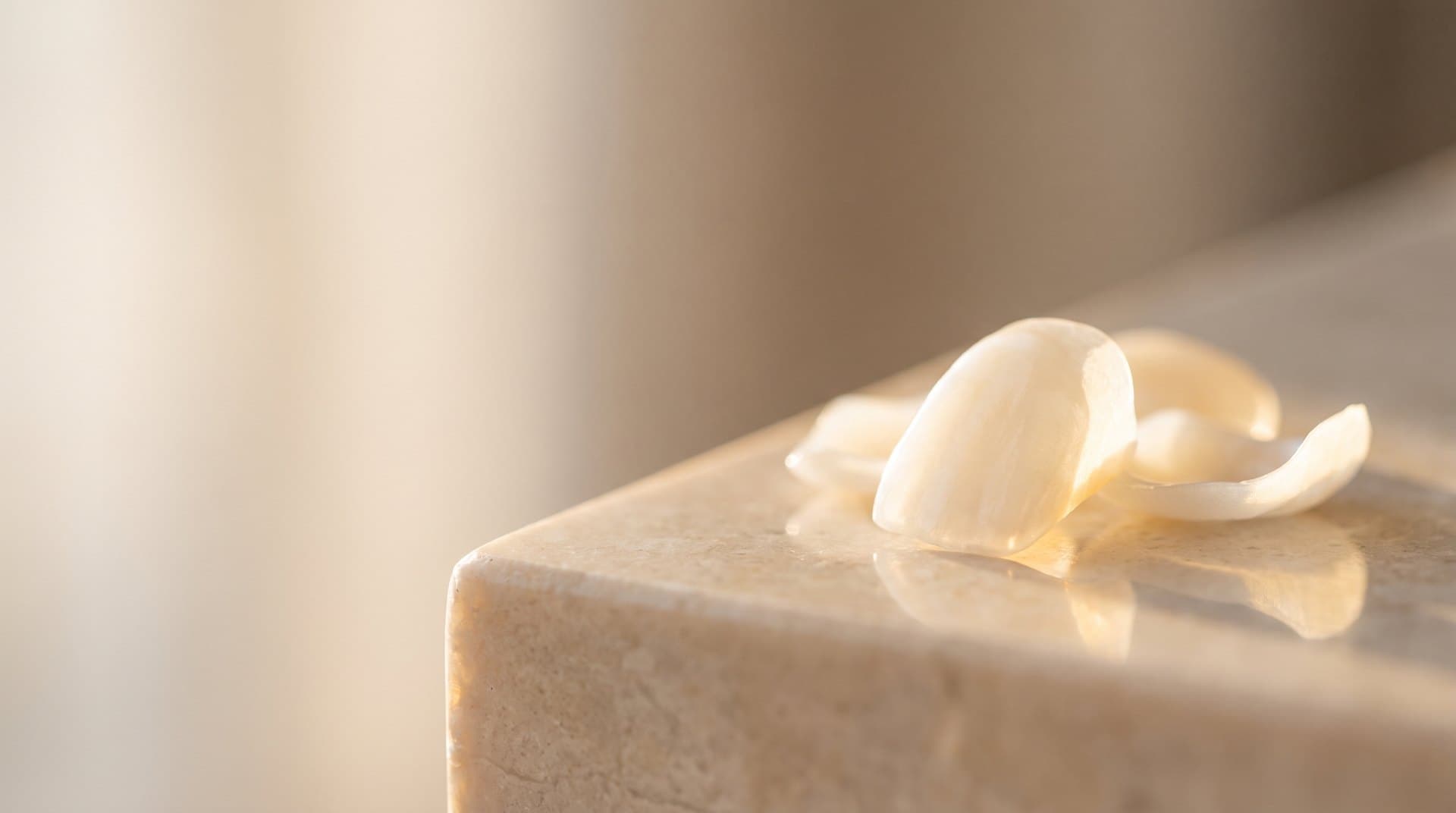 Thin porcelain dental veneer shells, slim tooth-shaped wafers, photographed in warm light