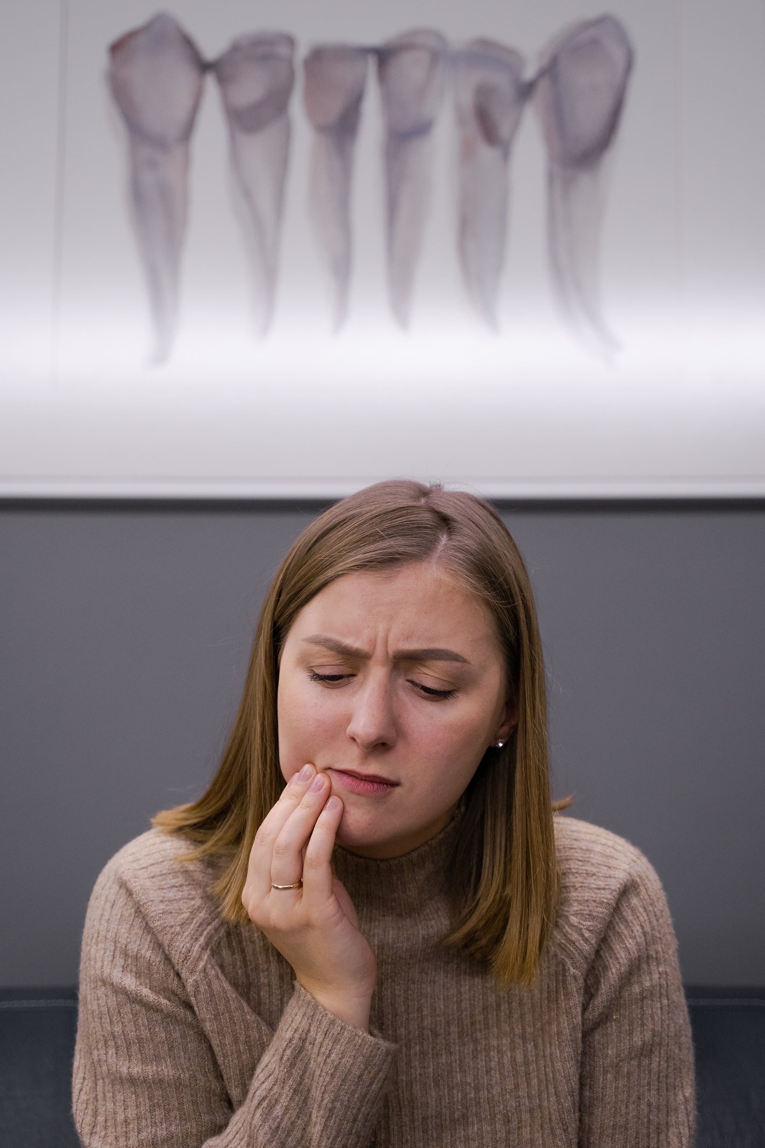 A woman with toothache from a problematic wisdom tooth at Align Dental Surgery